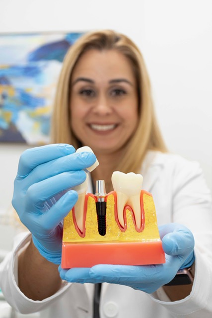 Dr. Narvaez holding a dental implant model and showing it toward the camera.